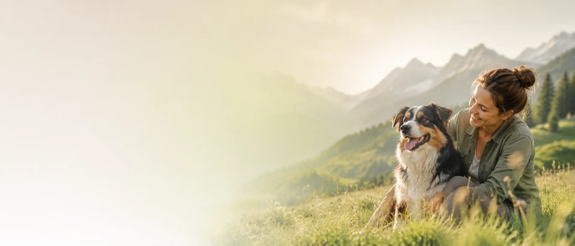 Frau mit ihrem Hund auf einer sonnigen Bergwiese